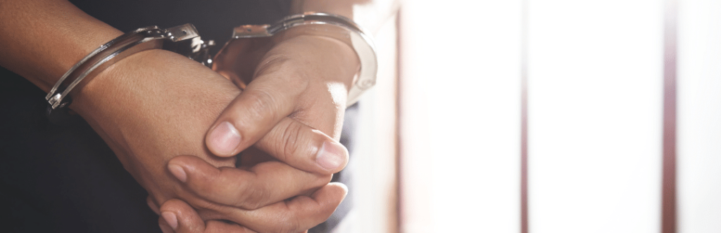 hands in handcuffs in front of jail cell