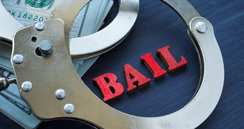 handcuffs on stacks of money red wood letters spell bail