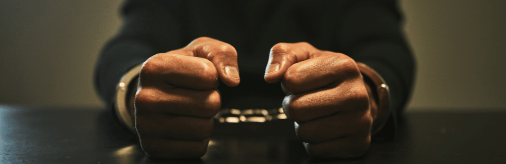 man arrested sitting at table in handcuffs