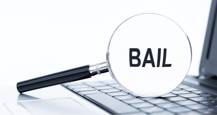 magnifying glass sitting on laptop looking at word bail 